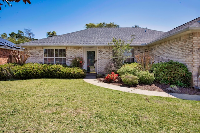 ranch-style home with brick siding, a front yard, and a shingled roof