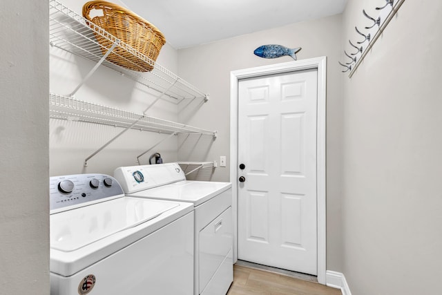 laundry area featuring independent washer and dryer, laundry area, baseboards, and light wood-style floors