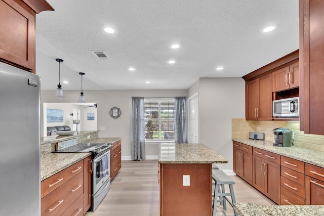 kitchen with appliances with stainless steel finishes, light wood finished floors, a textured ceiling, and visible vents