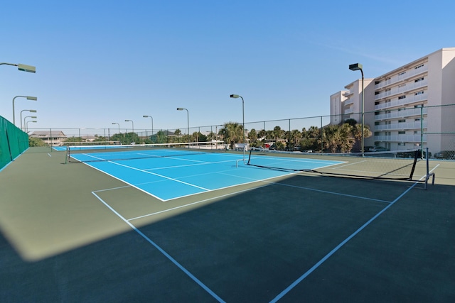view of tennis court featuring community basketball court and fence