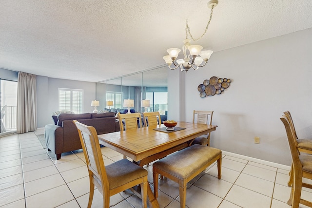 dining space featuring a chandelier, a textured ceiling, light tile patterned flooring, and baseboards
