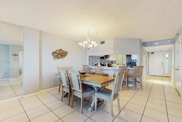 dining space featuring visible vents, a textured ceiling, an inviting chandelier, and light tile patterned flooring