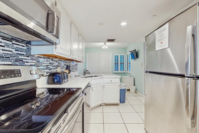 kitchen with white cabinets, visible vents, appliances with stainless steel finishes, a sink, and decorative backsplash