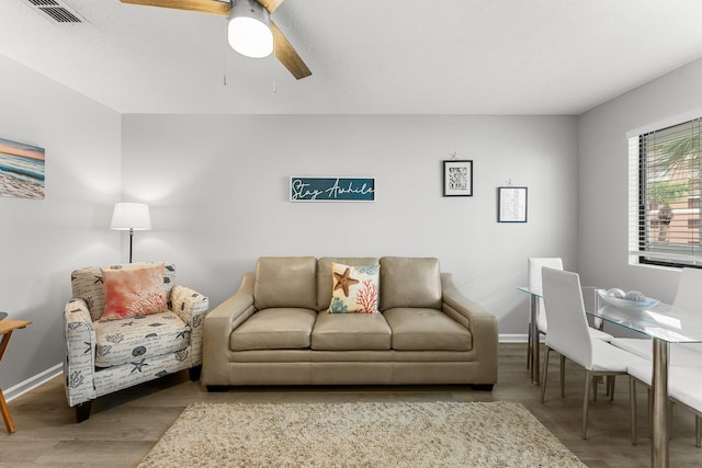 living room with visible vents, ceiling fan, baseboards, and wood finished floors