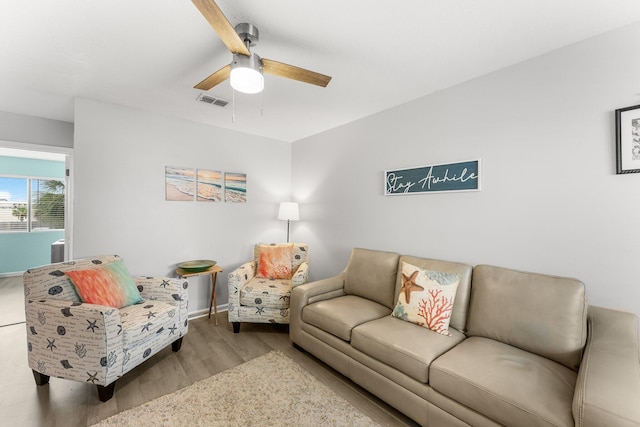 living room featuring wood finished floors, baseboards, a ceiling fan, and visible vents