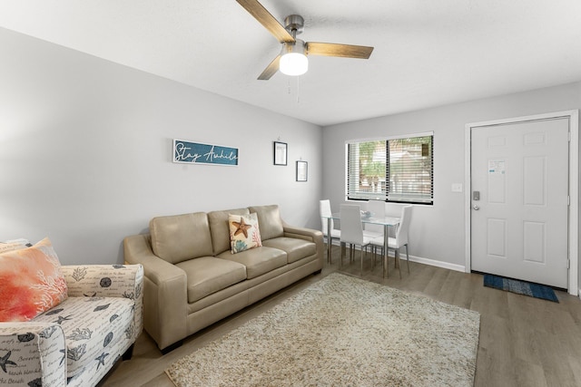 living room with light wood-style flooring, baseboards, and a ceiling fan