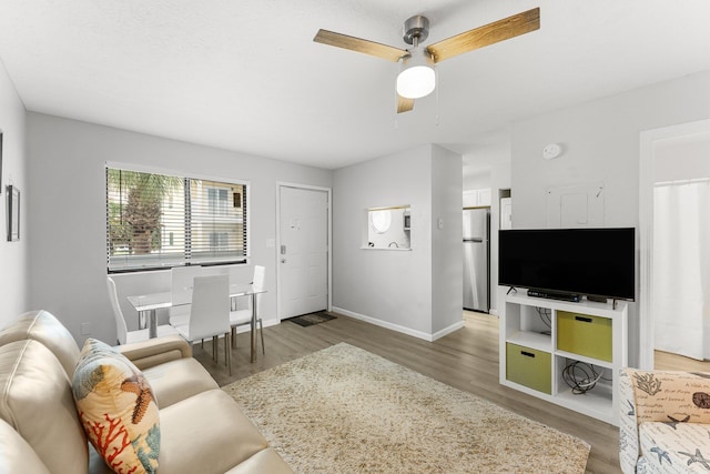 living area with wood finished floors, ceiling fan, and baseboards