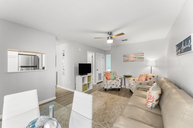 living area with wood finished floors, baseboards, a ceiling fan, and visible vents