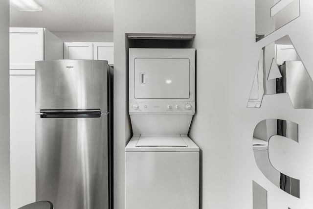 washroom featuring stacked washer / dryer, laundry area, and a textured ceiling
