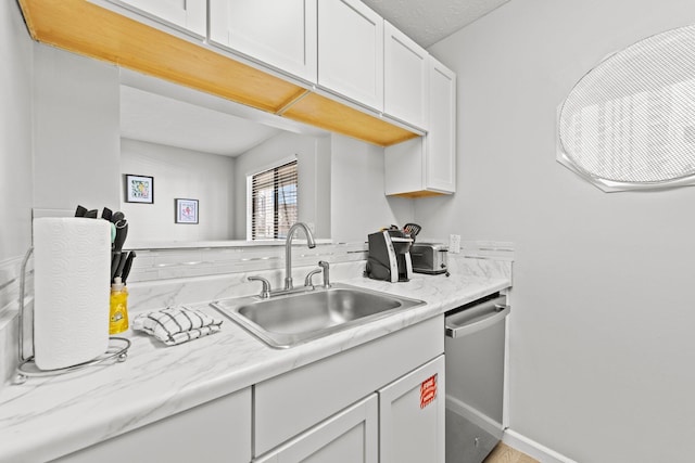kitchen with light countertops, dishwasher, a sink, and white cabinetry