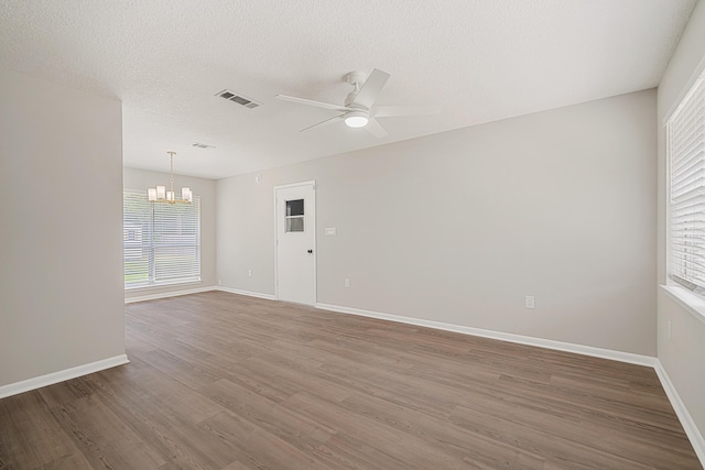 2899 Wisteria Ave, Crestview, FL 32539 - empty room with a chandelier, ceiling fan, wood finished floors, healthy amount of natural light, and a textured ceiling