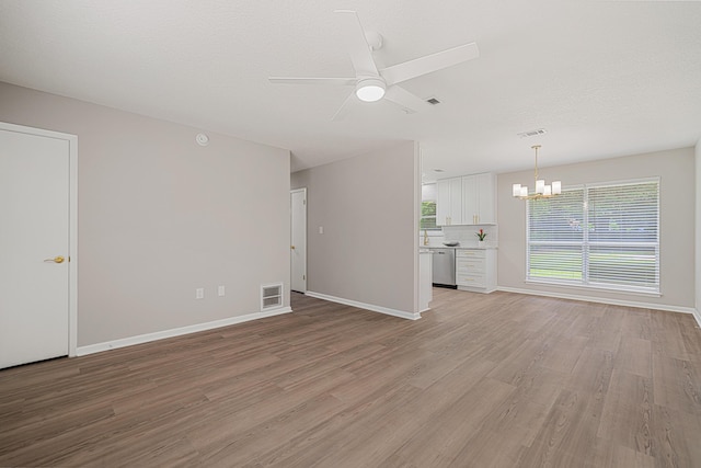2899 Wisteria Ave, Crestview, FL 32539 - unfurnished living room featuring a chandelier, a ceiling fan, light wood-style flooring, and baseboards