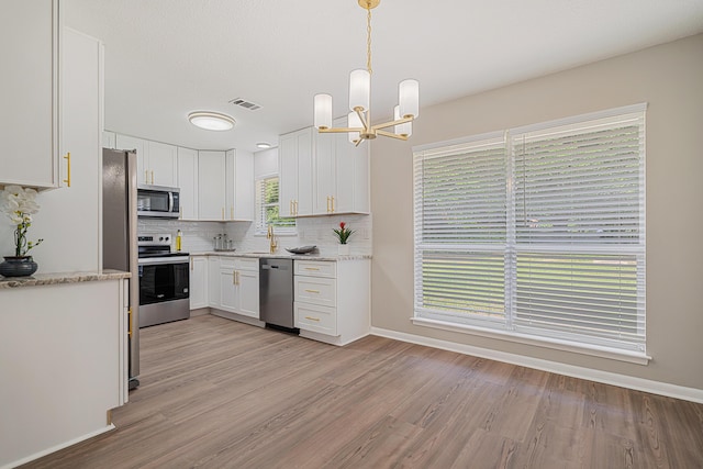 2899 Wisteria Ave, Crestview, FL 32539 - kitchen featuring appliances with stainless steel finishes, a chandelier, white cabinetry, and backsplash