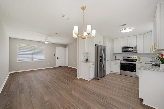 2899 Wisteria Ave, Crestview, FL 32539 - kitchen featuring stainless steel appliances, a sink, decorative backsplash, wood finished floors, and open floor plan