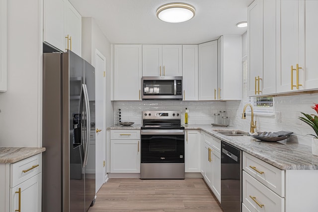 2899 Wisteria Ave, Crestview, FL 32539 - kitchen featuring appliances with stainless steel finishes, a sink, white cabinets, light wood-style flooring, and backsplash