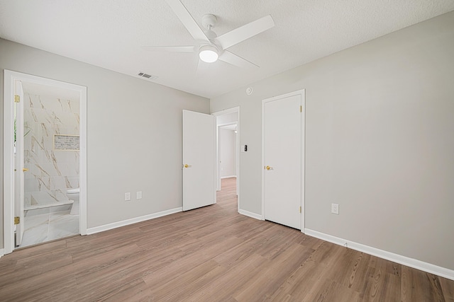 2899 Wisteria Ave, Crestview, FL 32539 - unfurnished bedroom featuring wood finished floors, baseboards, ensuite bathroom, ceiling fan, and a textured ceiling