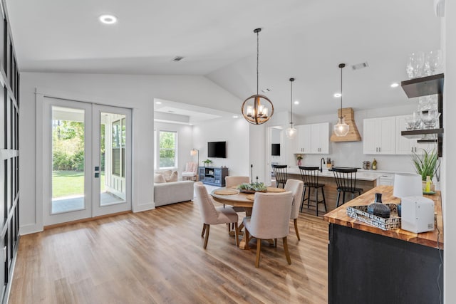 dining space featuring a notable chandelier, light wood-style flooring, and lofted ceiling
