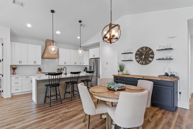 dining area with visible vents, wood finished floors, and lofted ceiling