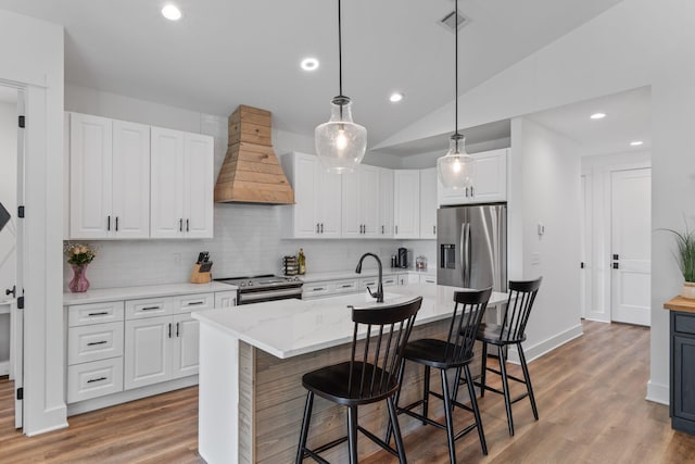 kitchen with wood finished floors, backsplash, custom range hood, and appliances with stainless steel finishes