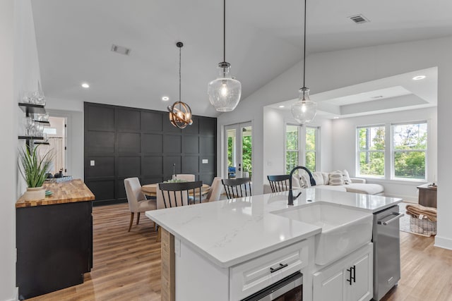 kitchen with visible vents, open floor plan, light wood finished floors, and a sink
