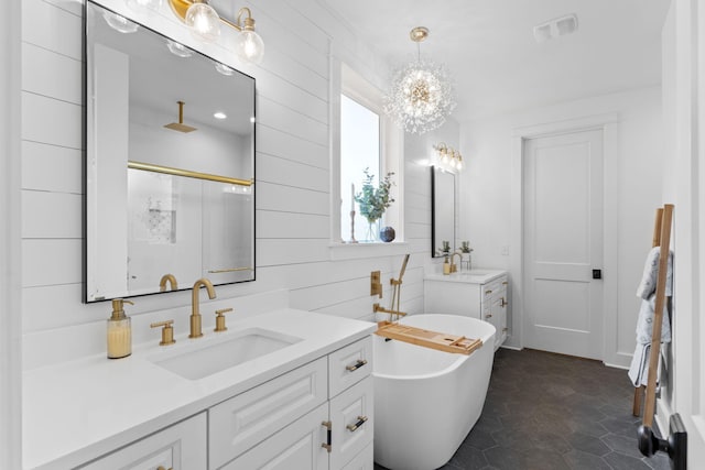 bathroom with a sink, a stall shower, an inviting chandelier, two vanities, and a freestanding tub
