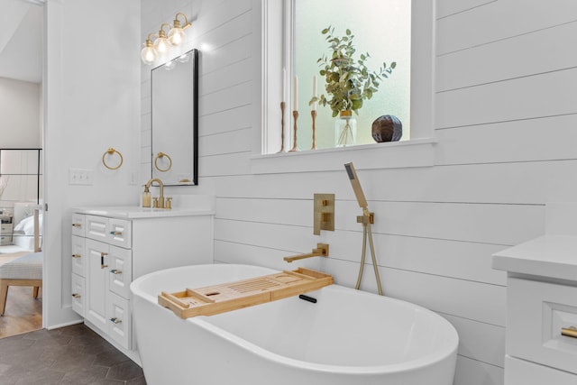 full bath featuring a freestanding bath, stone finish floor, ensuite bathroom, and vanity