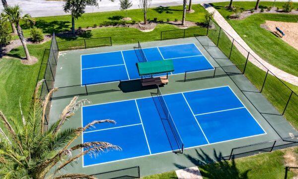 view of tennis court with a lawn and fence