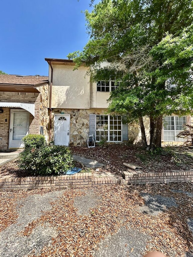 rear view of property featuring stucco siding and stone siding