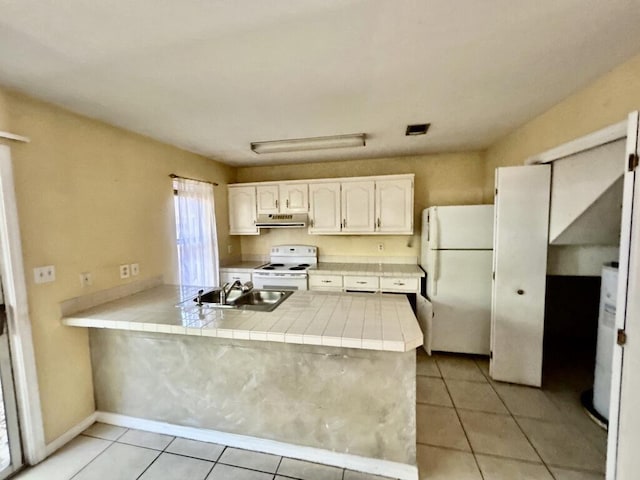 kitchen with a sink, white appliances, a peninsula, under cabinet range hood, and tile counters