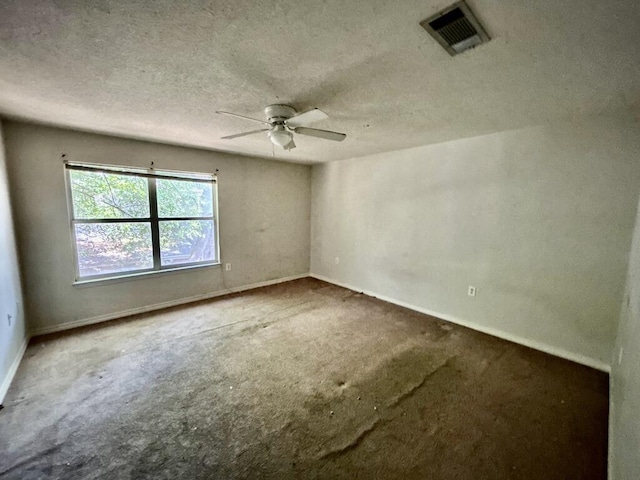 carpeted empty room with visible vents, ceiling fan, baseboards, and a textured ceiling