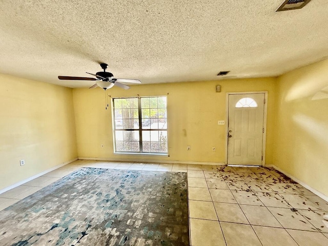 tiled foyer featuring a textured ceiling, ceiling fan, baseboards, and visible vents