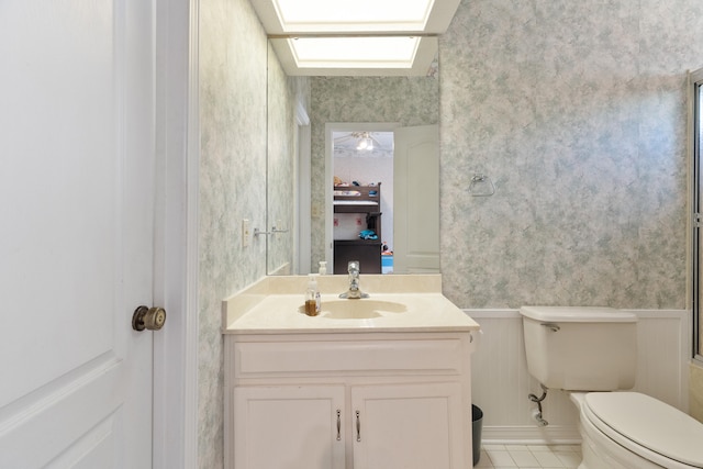 809 Main St, Destin, FL 32541 - bathroom with vanity, a wainscoted wall, toilet, tile patterned floors, and wallpapered walls