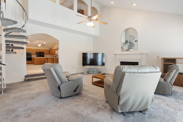 809 Main St, Destin, FL 32541 - living area with arched walkways, a tiled fireplace, a ceiling fan, stairs, and light colored carpet