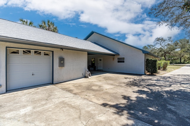 809 Main St, Destin, FL 32541 - view of side of property featuring an attached garage, stucco siding, a shingled roof, and concrete driveway