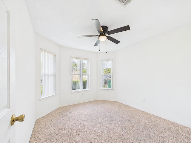 carpeted spare room featuring ceiling fan, baseboards, and visible vents