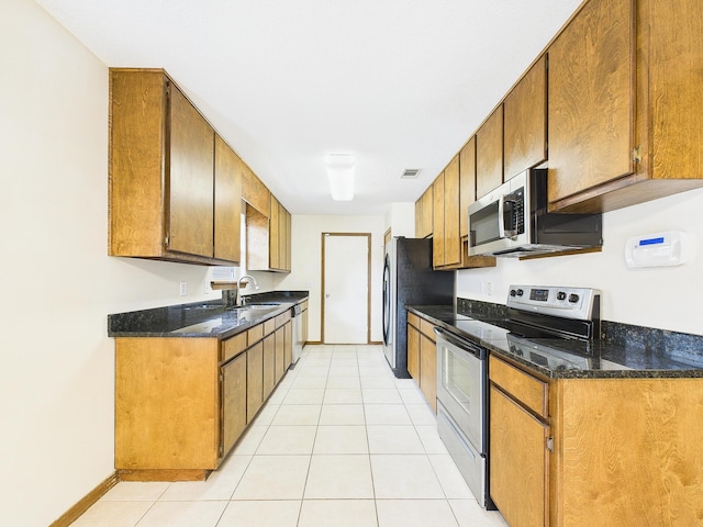 kitchen with visible vents, a sink, appliances with stainless steel finishes, brown cabinetry, and light tile patterned flooring