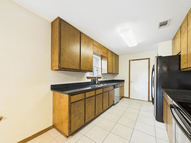 kitchen featuring light tile patterned floors, visible vents, appliances with stainless steel finishes, a sink, and baseboards
