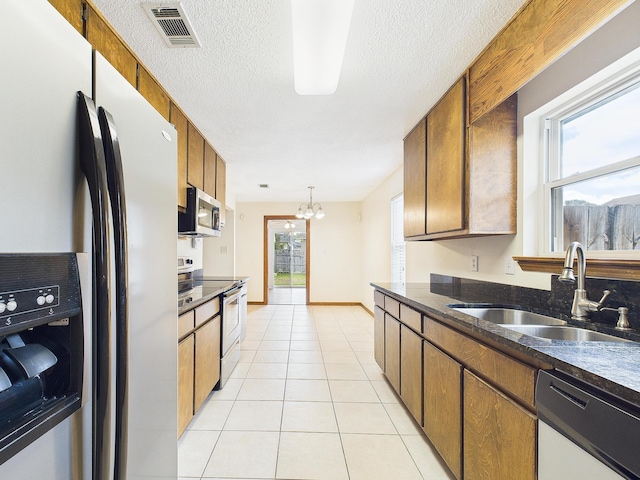 kitchen with visible vents, light tile patterned floors, a sink, appliances with stainless steel finishes, and brown cabinets