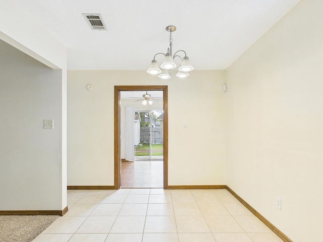 unfurnished room with ceiling fan with notable chandelier, light tile patterned floors, baseboards, and visible vents