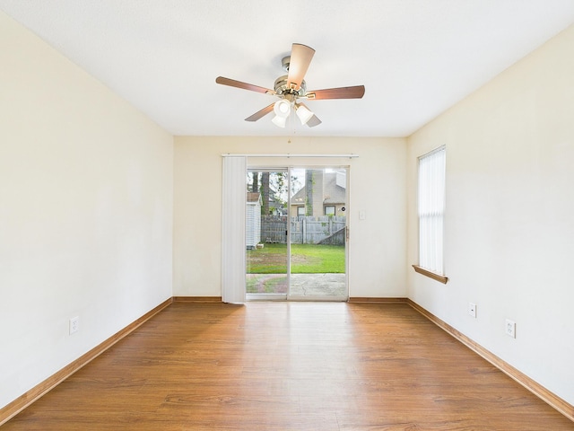 spare room with wood finished floors, ceiling fan, and baseboards