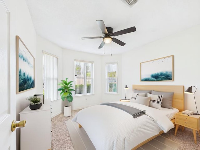 carpeted bedroom with visible vents, baseboards, and a ceiling fan