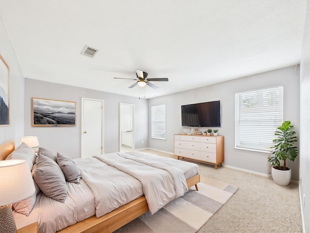 carpeted bedroom with ceiling fan, baseboards, ensuite bathroom, and visible vents