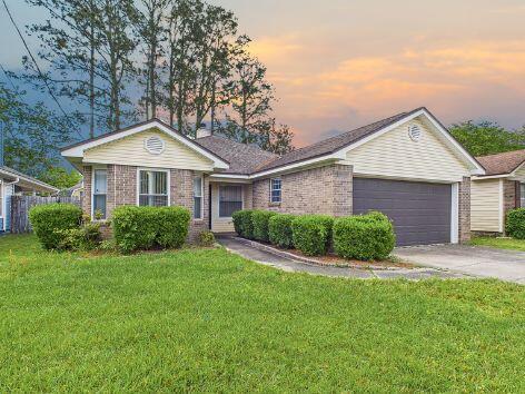 ranch-style home with concrete driveway, a yard, brick siding, and an attached garage