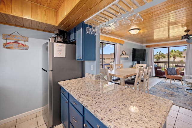 kitchen with light tile patterned floors, wooden ceiling, freestanding refrigerator, a peninsula, and blue cabinets