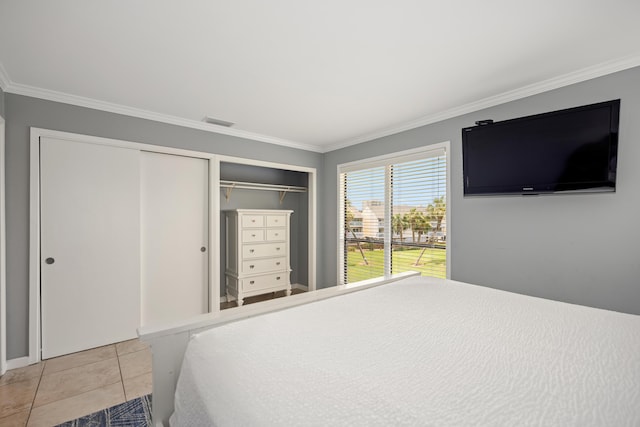 tiled bedroom featuring ornamental molding, visible vents, and multiple closets