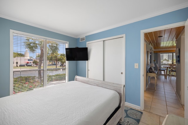 bedroom with visible vents, baseboards, a closet, crown molding, and light tile patterned flooring
