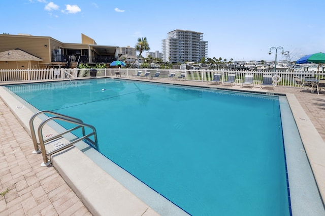 community pool with a patio area and fence