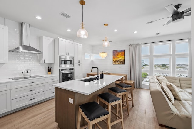 34 Gulf Breeze Ct, Destin, FL 32541 - kitchen featuring visible vents, a sink, wall chimney range hood, appliances with stainless steel finishes, and light wood-style flooring