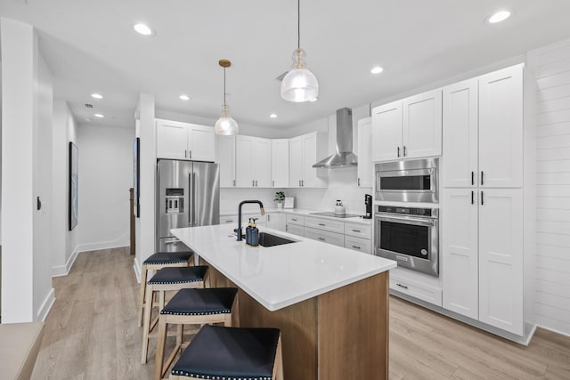 34 Gulf Breeze Ct, Destin, FL 32541 - kitchen with light wood-style floors, wall chimney exhaust hood, a kitchen bar, appliances with stainless steel finishes, and a sink
