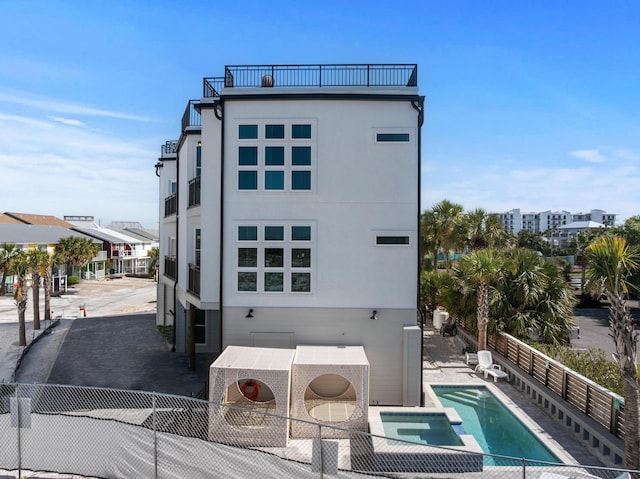 34 Gulf Breeze Ct, Destin, FL 32541 - back of house featuring stucco siding, a pool with connected hot tub, a patio, and fence